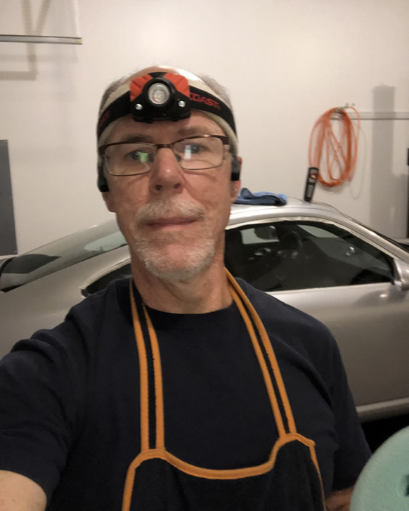 Steve Drobot Wearing Headlamp for Fixing Car's Imperfections on the Ceramic Coating of the Porsche 911 Car that He's Detailing.